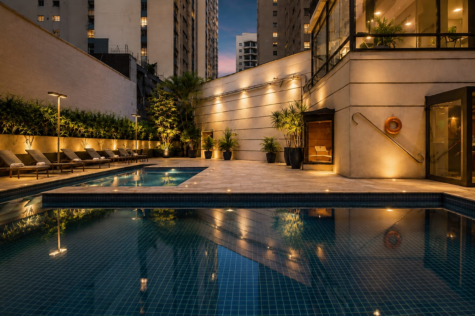 Piscina externa ao entardecer com vista dos prédios de São Paulo